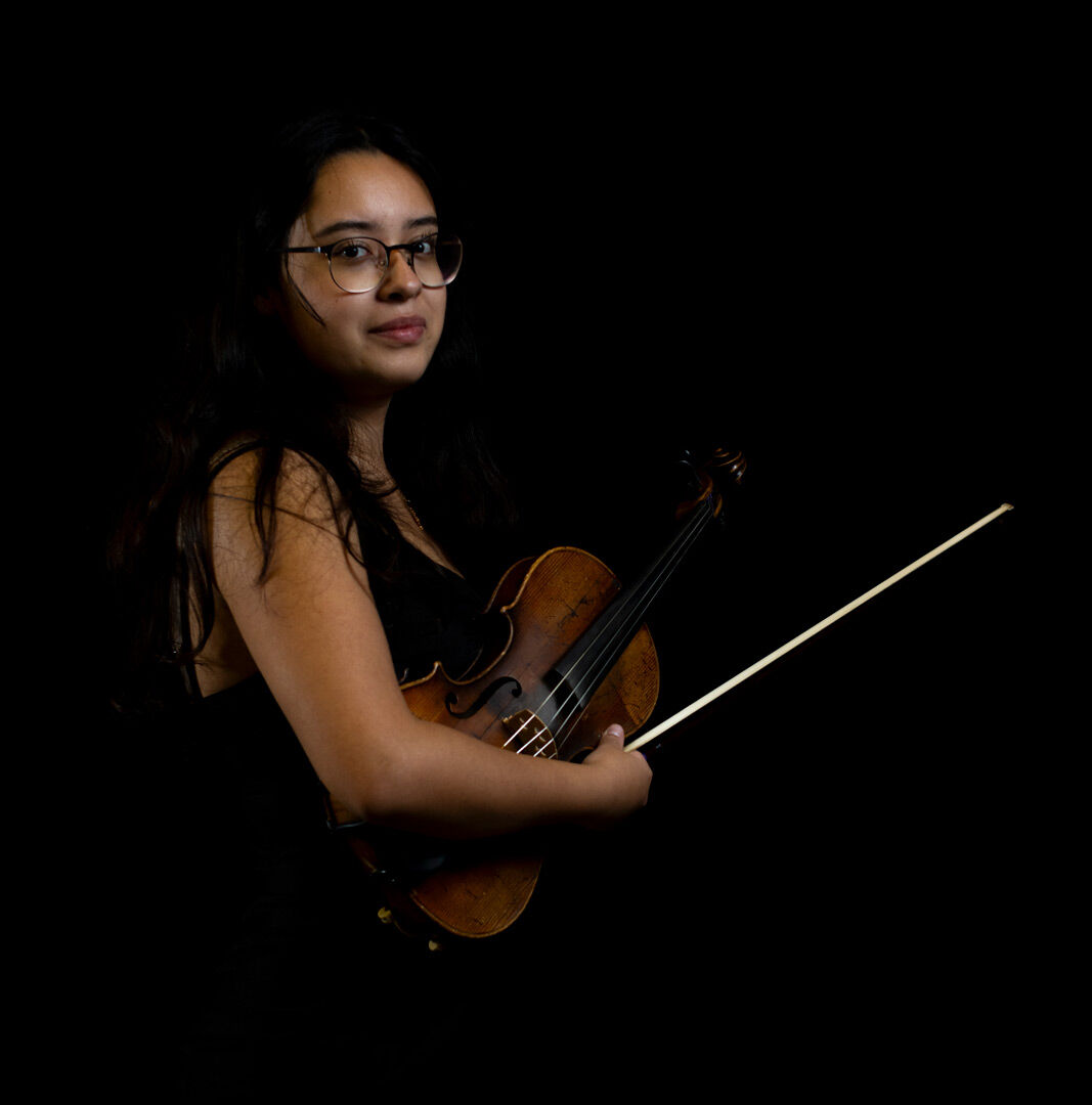 Emily Andrade Gonzalez stands with her violin. She has played mariachi music for seven years and violin for ten.(Alex Hernandez/Ethos)