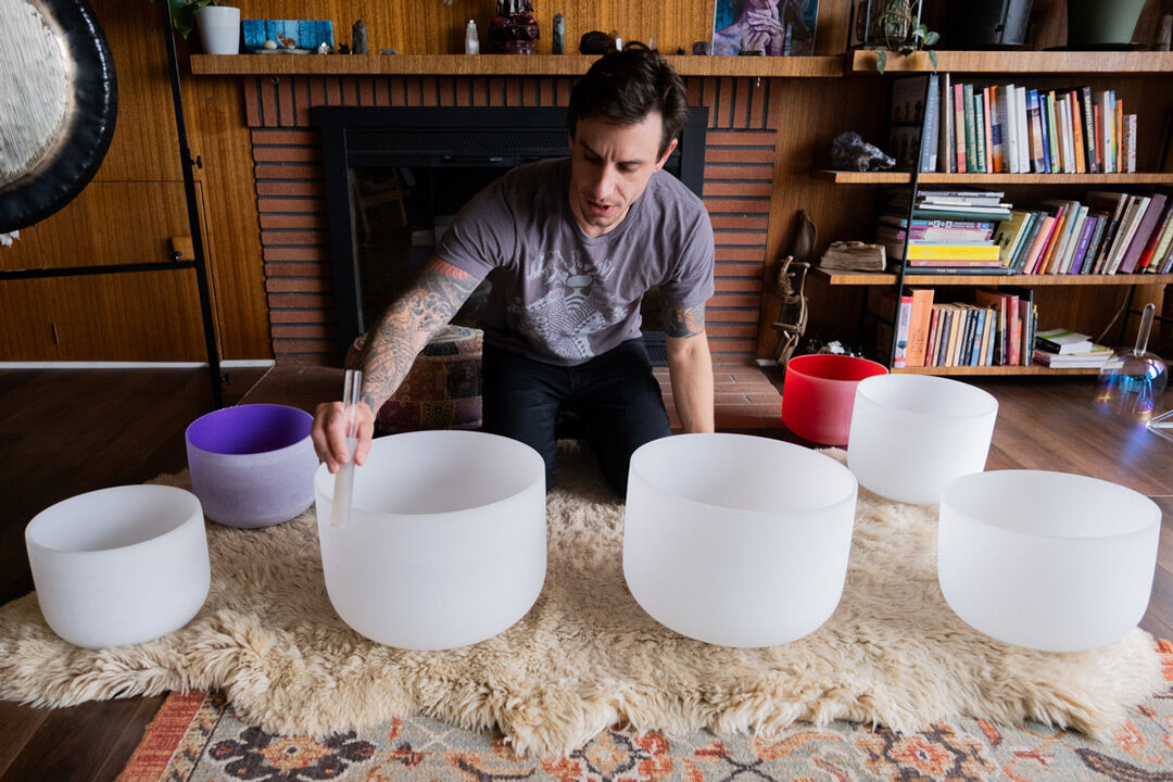 While preparing to play an assortment of singing bowls, Hin describes the purpose of each note. He says he is still working to create his own style of play. (Shane Balian/Ethos)