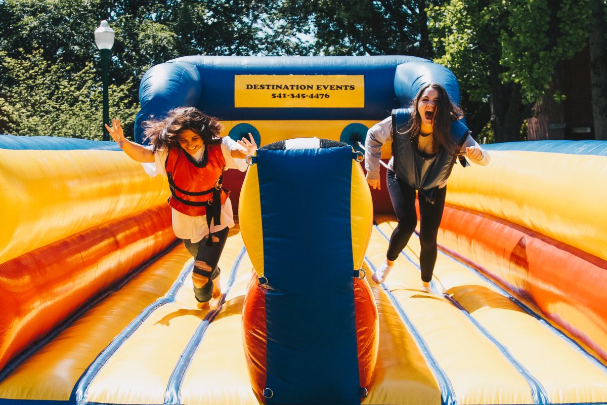 Claire Bruning (left) and Julia Troxell (right) compete to reach the furthest distance on a bungee run inflatable.